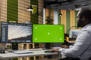 Yenilenebilir enerji entegrasyonunu geliştirmek için yeşil ekran bilgisayar kullanan mühendis. Ar-Ge uzmanı, eko güç hatlarının altyapısını tasarlamak için ofisteki model bilgisayarı kullanır