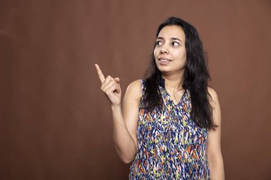 Güzel Hintli bir kadın boş fotokopi alanını işaret ederek ürün ya da reklam sunuyor. Günlük giysiler içinde güzel bir kadın, işaret parmağıyla sola doğru hareket ediyor..