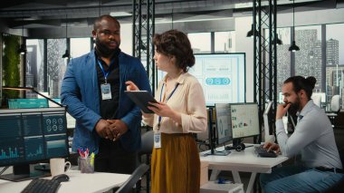 Çeşitli işçiler büyüme stratejisini geliştirmek için dijital araçlar ve analizler kullanmakta, modern ofis ortamında yenilik ve kalkınmayı teşvik etmek için tablet üzerindeki mali görüşleri gözden geçirmektedir..