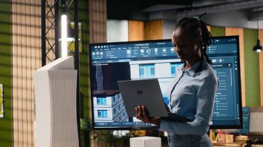 Siyah emlak mühendisi şehir planlamada kullanılan 3D kuleler ve dijital planlar, site hazırlama planının kesinleştirilmesi ve konut projesi için yapısal konut tasarımı üzerinde çalışıyor.