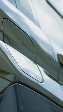 Sürücünün EV aküsünü şarj ettiği, sürdürülebilir elektrikli motora güç veren, düşük açılı atışın dikey videosu. Kişi temiz enerji kaynağına takılarak EV arabasının bataryasını şarj eder