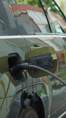 Dikey video, EV çevre dostu SUV aracının araç giriş kapağını şarj ettikten sonra kapatın. Sürücü, bitirdikten sonra alternatif enerji tabanlı elektrikli aracın şarj kapağını kapatıyor
