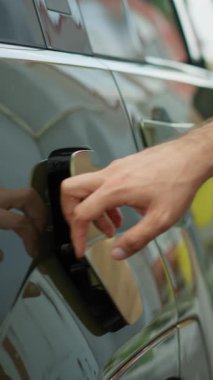 Sürücünün elektrikli araba kapağını açtığı dikey video, şarj pilini şarj etmek için elektrik kablosu konnektörü takıyor. Adam, yeniden tedarik etmek için EV otomobilinin araç giriş portunu açıyor