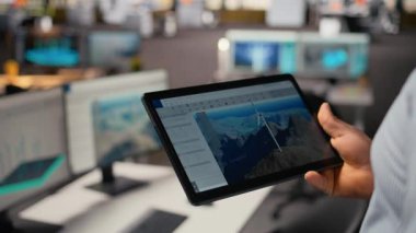 Rüzgâr türbini CAD tasarımı üzerinde çalışmak için tablet kullanarak sürdürülebilir enerji araştırması yaparak, ofisteki mühendisi kapat. A kamerasında rüzgar enerjisi jeneratörünün dijital modellemesini yapan işçiler.