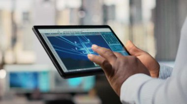 Ofisteki elektrik santrallerini tasarlamak için tablet kullanan mühendisi kapatın. Ar-Ge uzmanı iletim kulesi sistemlerini optimize etmek için cihaz üzerinde CAD yazılımı kullanır. Kamera B