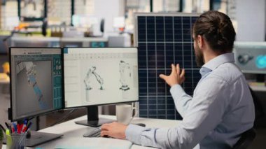 Sürdürülebilirlik uzmanı güneş paneli montajı için üretim hatları tasarlamak için bilgisayar üzerinde CAD programı kullanır. İşçi, güneş pillerini geliştirmek için simülasyon araçları çalıştırıyor, temiz enerji adaptasyonunu hızlandırıyor, kamera B