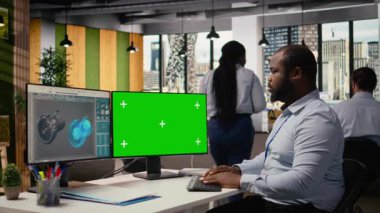 Modern ofisteki yenilenebilir enerji mühendisi yeşil ekran bilgisayar kullanarak rüzgar türbini teknolojisini geliştiriyor, güç üretimini optimize etmek için yeni malzemeler ve tasarımlar uyguluyor, kamera A