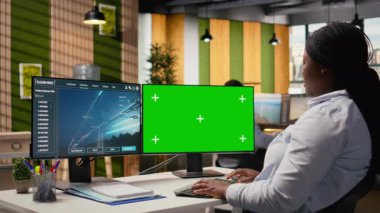 Mühendis, izole ekran bilgisayarındaki güç hatlarını analiz paneline bakıyor ve ölçümleri gösteriyor. Afrika kökenli Amerikalı bir kadın, iletim kulesi sensör verilerini ve kamera A 'yı analiz etmek için ofisinde model bilgisayar kullanıyor.