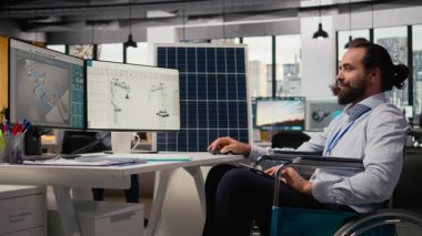 ArGe ofisinde belden aşağısı felçli bir adam yeşil teknoloji güneş panelleri tasarlıyor. Tekerlekli sandalyedeki engelli çalışanlar güneş pillerini, temiz enerji üretimini ve kamera A 'yı geliştirmek için simülasyon çalıştırıyorlar.