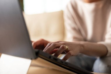 Uzaktan çalışırken dizüstü bilgisayarda yazan kadın ellerine odaklan. Girişimci, çağdaş dijital çalışma rutini ve verimliliğinin gösterildiği evden gelen raporları ve teklifleri güncelliyor.