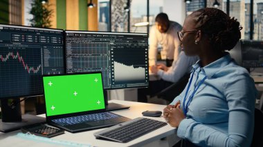 Ofisteki aksesuar firması, izole ekran dizüstü bilgisayarında video dersinden yeni ticaret stratejileri öğreniyor. Forx şirketindeki Afrikalı Amerikalı kadın model defter kullanıyor.