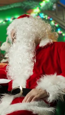 Noel kostümü giymiş dikey videolu kişi uyuya kaldıktan ve çocuklara hediye teslimatında geç kaldıktan sonra uyarıldı. Noel Baba koltukta uyuduktan sonra uyanır ve mektupları okur.