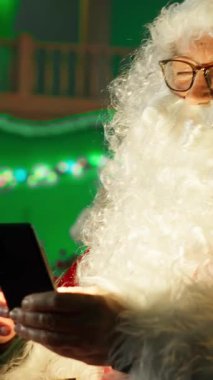 Noel Baba rolünü oynayan dikey videocu çocuk cep telefonuyla hediye isteğine yanıt veriyor. Işıkla aydınlatılmış sakallı Noel Baba çocuklara Noel için telefon kullanarak ne istediklerini soruyor.