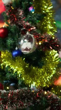 Noel çam ağacının renkli çelenklerle dolu olduğu dikey video ve Noel Baba çantasının yanında hediyelerle asılı duran toplar. Boş Noel Baba atölyesinde tuhaf bir festival havası var.