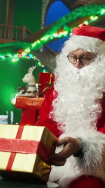 Noel Baba 'nın Noel Baba' yı canlandırdığı dikey video bayram neşesini yayıyor ve gönderilmek üzere hediyeler hazırlıyor. Noel Baba gibi giyinmiş bir adam neşeli bir ortam yaratıp hediyeler dağıtıyor.