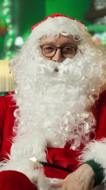 Noel Baba 'nın bu yıl iyi davranan çocuklarla internette video görüşmesi yaptığı dikey video görüntüsü. Sahte sakal takan yaşlı bir adam internet video konferansı yapıyor, çocukları ziyaret etmeye hazırlanıyor, kamera A