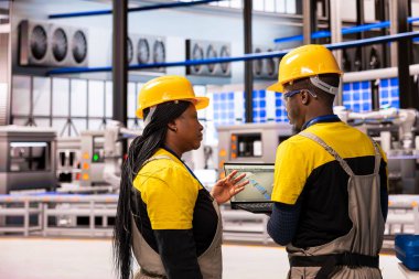 Otomatik fabrika mühendisleri dizüstü bilgisayardaki endüstriyel yazılımla üretim hattının performansını izliyor. Akıllı üretim tesisi, kesinlik için robotik sistemler ve otonom taşıma bantlarına sahiptir..