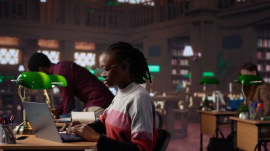 Üniversite öğrencisi kampüs kütüphanesinde bir arkadaşıyla el yazısı notlarını tamamlamak için sınav hazırlığı yapıyor. Veritabanından bilgi paylaşan kızlar. Kamera A.