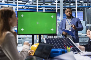 Güneş panelleri, kroma anahtar ekran kullanarak toplantı düzenleyen fabrika yöneticilerini üretiyor. Fotovoltaik fabrika yönetimi yeşil ekran monitörü kullanarak yükseltme notları alıyor