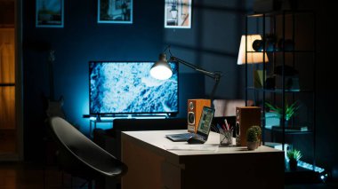 Şık bir ev ofisi olan şehir merkezli bir dairede modern oturma odası. Ahşap zemin, dekoratif bitkiler ve bilgisayar masası rahat bir yaşam tarzı için rahat, minimalist bir iç tasarım oluşturur..