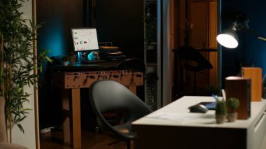 Geniş bir ev ofisi ve ahşap mobilyaları olan şık bir daire, rahat bir TV salonu, dekoratif ev bitkileri ve minimalist bir tasarım modern, rahat bir çalışma alanı ve yaşam alanı oluşturur..