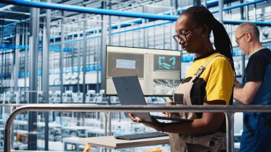 Gülümseyen mühendis akıllı fabrikayı denetliyor, dizüstü bilgisayardaki ölçümlere bakıyor. Sektör 4.0 'daki platformdaki mutlu teknisyen sensörlerle donatılmış, defter, kamera A ile donatılmış.