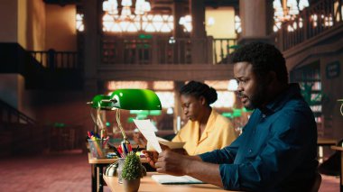 Afrika kökenli Amerikalı üniversite öğrencisi son dersten kalan teorik notları çalışmak için çabalıyor, sınava hazırlanmayı öğreniyor. Kampüs kütüphanesindeki sinirli genç. Kamera A.