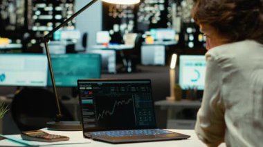 Küresel piyasa ilerleme eğilimlerini izleyen ve belgelendiren kadın analist, saatler sonra ofiste ön bilgi. Organizasyonel büyüme için finansal görüşler ve ekonomik analizler uygulanıyor. Kamera B.