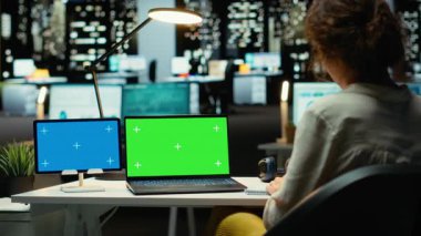 İşletme danışmanı, tablet ve dizüstü bilgisayarda bir yönetim projesi için raporları araştıran bir kopya alanı üzerinde çalışıyor. Gece geç saatlerde bilgi toplamak ve görevleri çözmek, mesai sonrası çalışmak. Kamera B.