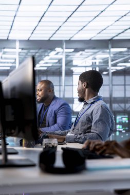 İdari ekip, veri merkezinin enerji tüketimini bileşenler arasında izlerken sunucu merkezinde konuşuyor ve eğleniyor. Algılayıcıların optimum olarak çalıştığından emin oluyor, rutin disk kontrolleri yapıyor.