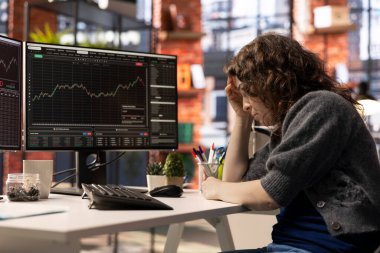 Hüsrana uğramış girişimci çift monitörlerde borsa büyümesini izliyor, eğilimleri ve likiditesi analiz ediyor. Ticaret arayüzü, istikrarsız bir pazarda bilgilendirilmiş alım-satım kararlarını mümkün kılar.