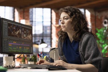 Odaklanmış editör kadın ajans ofisinde, dijital medyada yaratıcı bir yazılımda video montajı üzerinde çalışıyor. Çekimleri düzenlemek ve içerik yaratmak için çift monitör kullanan film yapımcısı, prodüksiyon sonrası.
