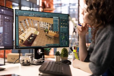 Genç tasarımcı, bilgisayar üzerindeki mimari yazılımla oda planlarını yapılandırmak için yeniden yapılandırma projesinde çalışıyor. Program, sanal mobilyaları ayarlamak için elementleri ya da varlıkları sürükleyip bırakmasına izin veriyor..