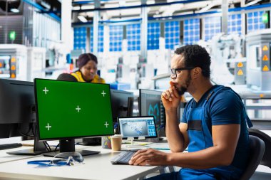 Photovoltaics fabrikası uzman sistem ayarları yeşil ekranda. Çalışan, güneş panellerinde dizüstü bilgisayar üzerinde çalışıyor. Montaj hatları yapılandırması için fabrika üretiyor..