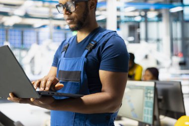 Yenilenebilir enerji tesislerindeki güneş enerjisi teknolojisini bilgisayar üzerinde test eden siyah mühendis, yazılım sorunları ve performans ölçümlerine odaklanıyor. Laptop 'ta çevre dostu endüstriyel operasyonlar.