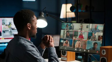 Evlerinden sanal bir web sitesine katılan meslektaşlar online görüşme için dizüstü bilgisayar kullanıyorlar. Genç Afro-Amerikalı adam kendini video konferansına kaptırdı. Kamera B.