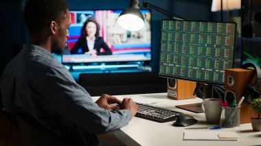 Finansal danışman, kripto döviz piyasasını çatı katındaki çalışma yerinden inceliyor, masaüstündeki online küresel döviz istatistiklerine bakıyor. Sermaye fonlarını güvence altına almak için hisse senedi analizi yapan adam. Kamera B.