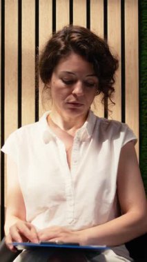 Koridorda kucağında CV ve belgelerle oturan, iş tecrübesi ve iş görüşmesi sırasında sunum niteliklerini inceleyen güveni tam bir gülümseme videosu portresi.