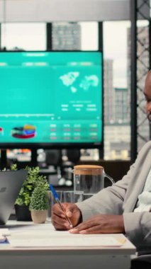 Dikey Video Siyah erkek aday, İK toplantısı sırasında iş sözleşmesi için istihdam belgesine imza atıyor, işe alım sürecini tamamlıyor ve yeni bir kariyer başlangıcı konusunda heyecanlı. Kamera.