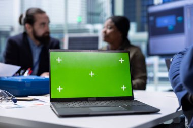 Üretim fabrikası uzmanı yeşil ekran dizüstü bilgisayar kullanarak sürdürülebilir üretim araştırma ve geliştirme verilerini analiz eder. Yatırımcılar, teknolojik yenilikleri değerlendirmek için model defterindeki belge dosyalarını gözden geçirirler