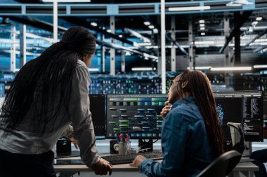 Teknisyenler, sunucu çiftliği altyapısında veri depolama programında birlikte çalışıyorlar. Bilgi işlem yapan bilişim uzmanları veri merkezi raflarını onarmak için bilgisayar üzerinde kod çalıştırıyorlar.