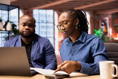 Siyahi bir çift kendi işlerinin mali ve vergilerini yönetiyor. Çatı katlarından uzaktan çalışırlarken masrafları ve gelirleri takip ediyorlar. Borçsuz bir yıl için vergi hesapları yapmak.