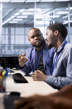 Veri merkezi yöneticisi iş arkadaşlarıyla tartışıyor, algoritmalar oluşturmak ve uygulamalar oluşturmak için programlama dilleri kullanıyor. Sunucu merkezi bilişim uzmanı iş arkadaşıyla konuşuyor, hata ayıklıyor ve kodu optimize ediyor