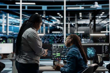 Veri merkezi mühendisleri konuşuyor, beyin fırtınası yapıyor, hataları tespit etmek için yapay zeka görselleştirme araçları kullanıyorlar. Sunucu merkezi çalışanları birlikte çalışarak yapay zekanın oluşturduğu içgörülere bakıyorlar.