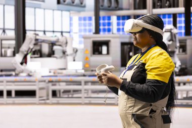 Otomasyon mühendisi sanal gerçekliği akıllı fabrikadaki üretim sürecine entegre ediyor. Siyahi kadın endüstrisi 4.0 işçi eğitim ve sorun giderme için VR kulaklık ve denetleyici kullanıyor.