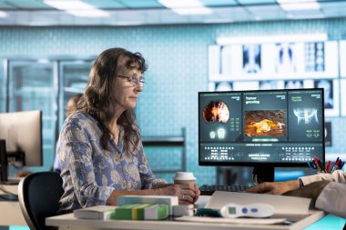 Genel pratisyen hekim, bir klinikte doğru rapor ve bakım yönetimi için tıbbi teknolojinin kullanılması, teşhis testi sonuçları hakkında kıdemli kadın hastaya danışmanlık yapar. Sağlık hizmeti sağlayıcısı.