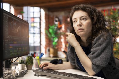 Ajans stüdyosunda çift monitörlü bir video düzenleyen video yapımcısı kadın zaman çizgisi düzenleme ve renk derecelendirme arasında birden fazla iş yapıyor. Profesyonel düzenleyici teknoloji araçları ve yazılım kullanır.