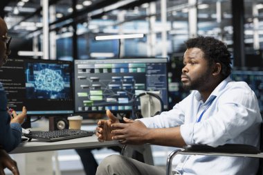 Tekerlekli sandalyedeki adam ve sunucu merkezi yöneticisi bilgisayar işleri için yapay zeka kullanıyor. Belden aşağısı felçli ve veri merkezinde çalışan mühendis makine öğrenme iş yükleri için yapay zeka kullan