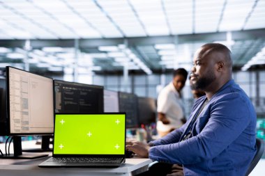 Veri merkezindeki teknisyen sunucuları kullanılabilir yazılım zayıflıklarından korumak için yeşil ekran dizüstü bilgisayardaki donanım sistemlerini güncelliyor. BT uzmanı hataları aramak için krom anahtar defteri kullanıyor