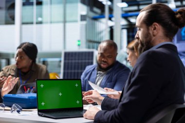 Fabrika yatırımcısı yatırım yapmadan önce mali tabloları incelemek için yeşil ekran dizüstü bilgisayar kullanıyor. Hissedarlar tarafından çalıştırılan yönetmeliklere uymayı değerlendirmek için kroma anahtar defteri kullanan bir uyum memuru